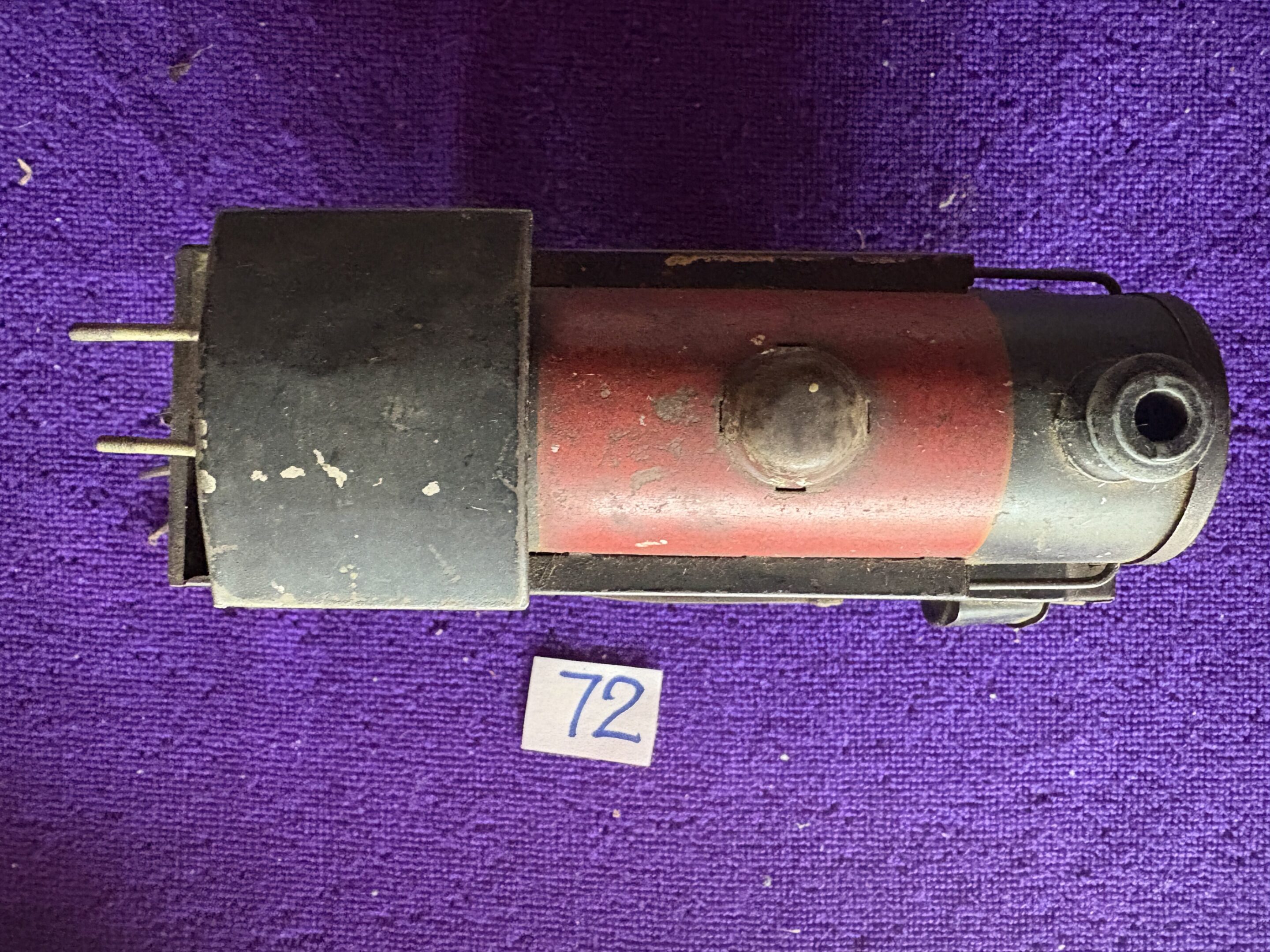 Close-up of a red vintage train car model on a purple surface.