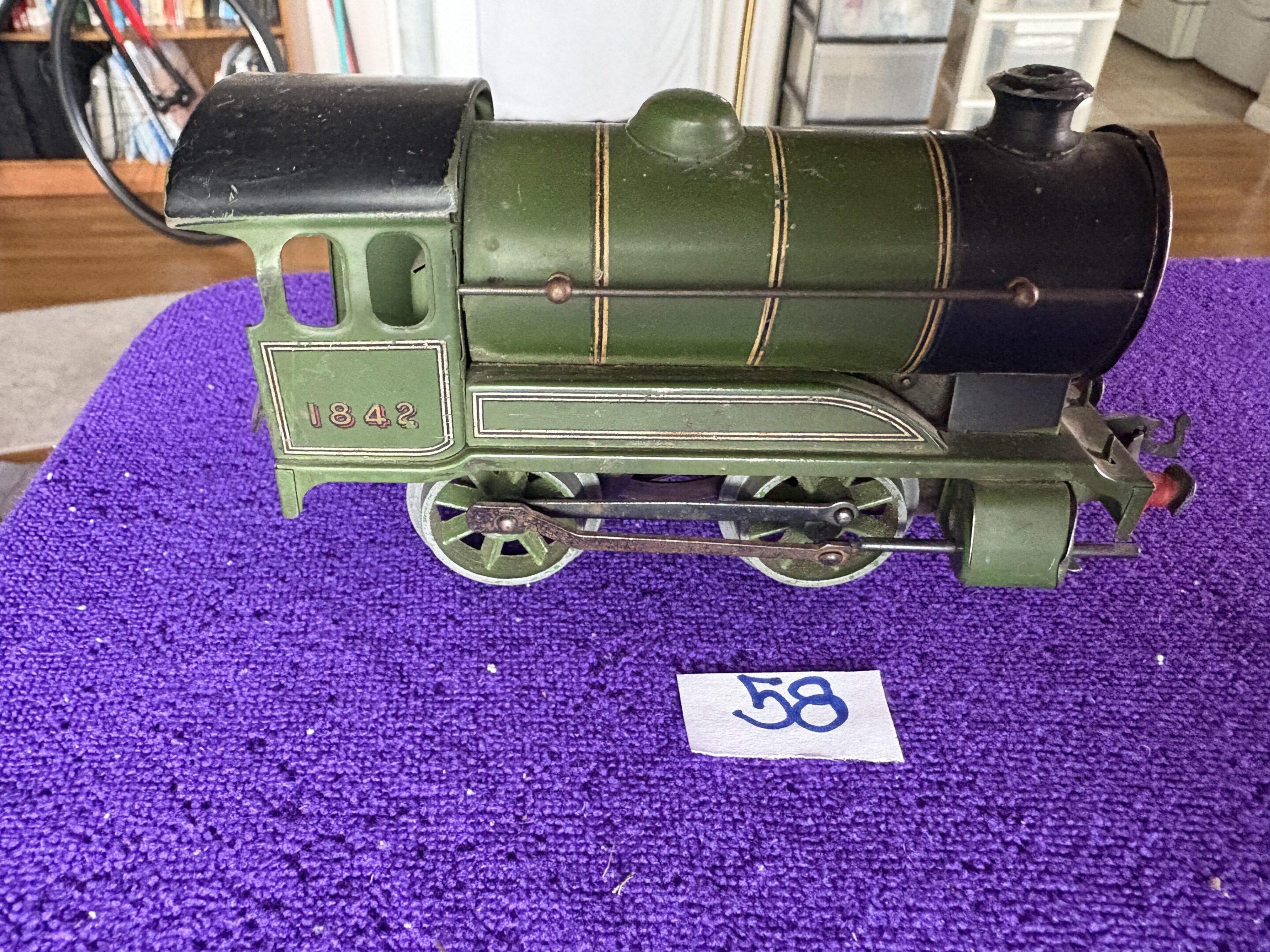Vintage green toy train engine on a purple surface.