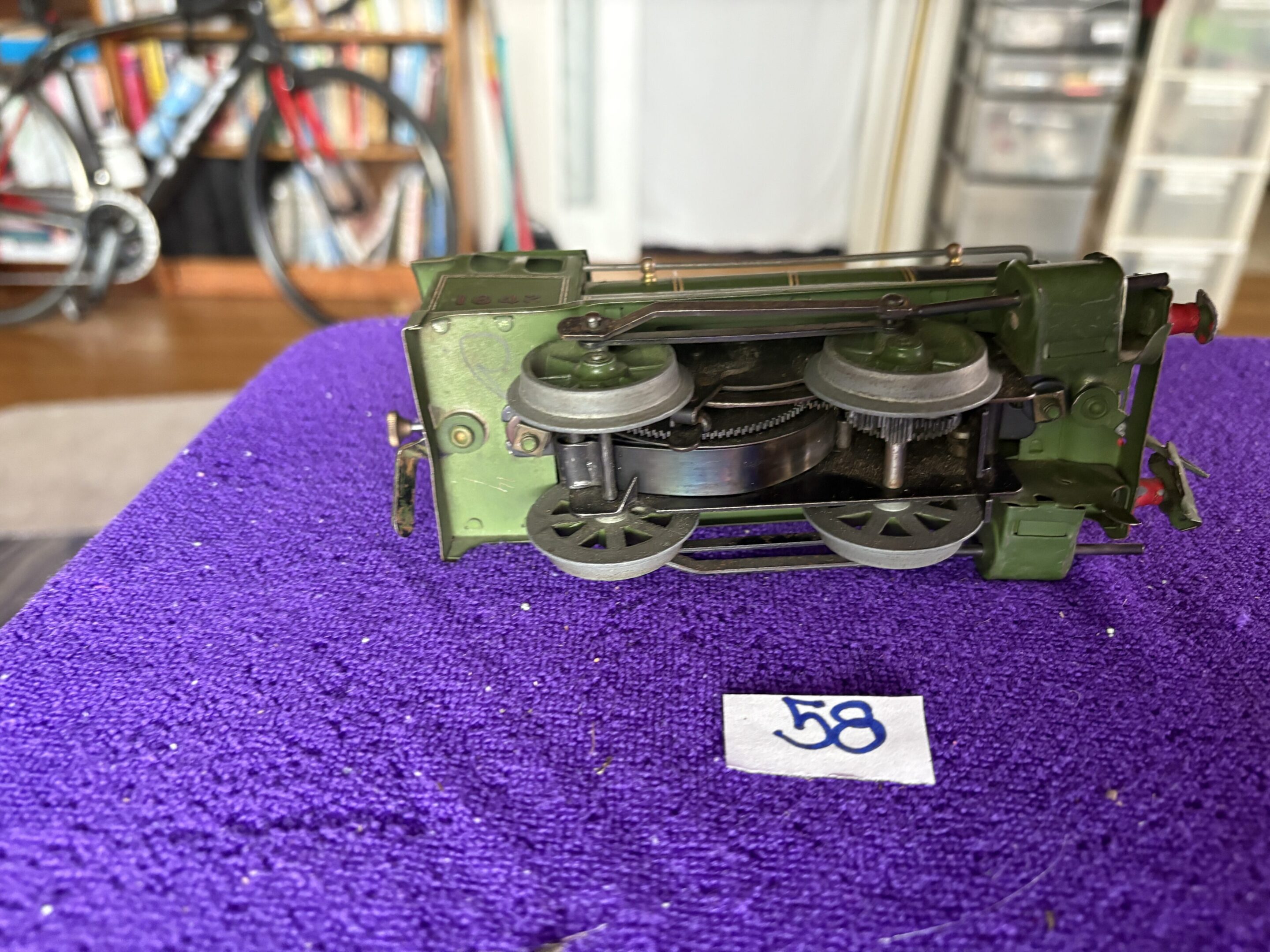 Close-up of a green model train displayed on a purple cloth with a number 38 tag.