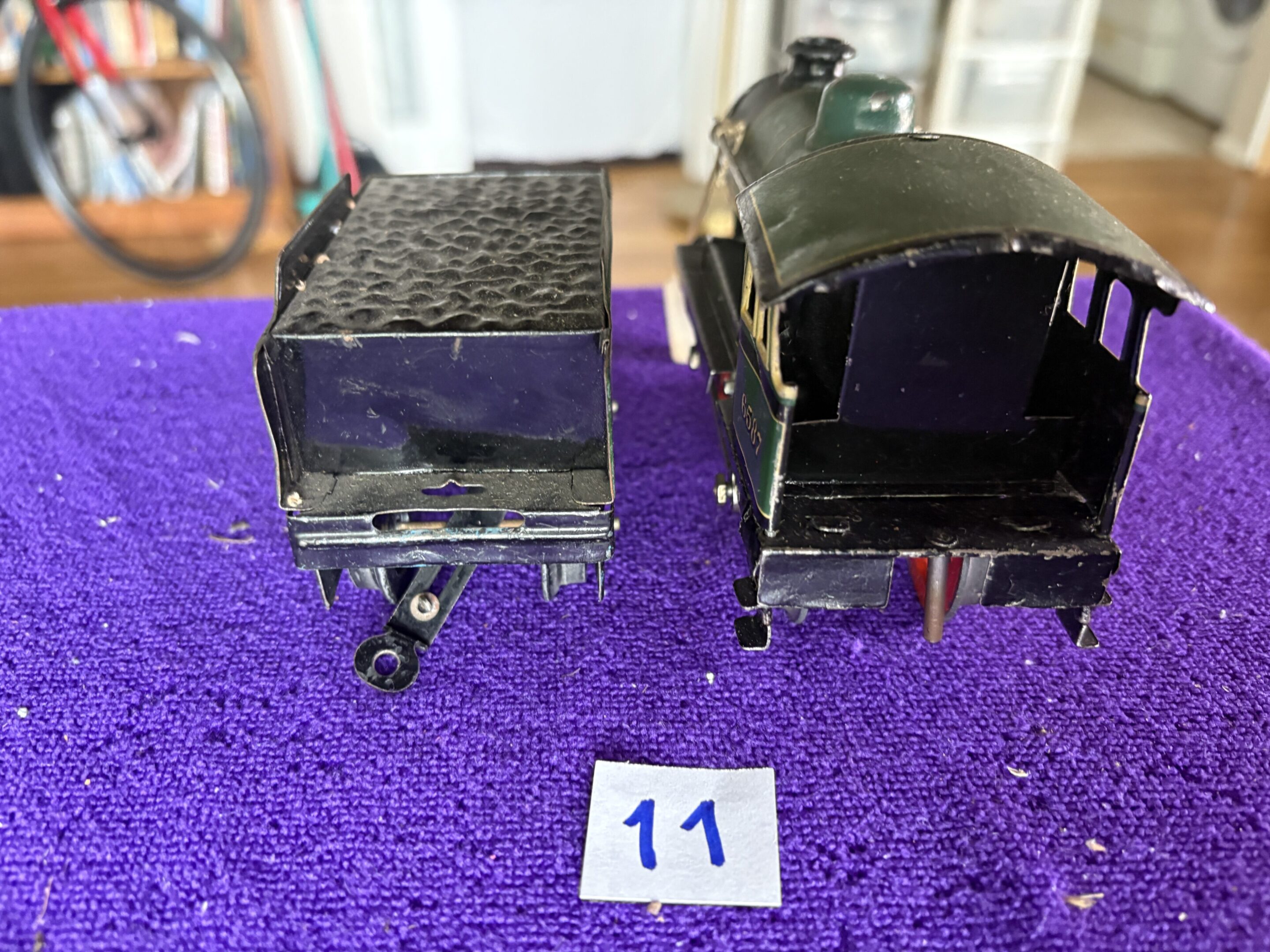 Vintage toy train engine and coal car on purple surface.