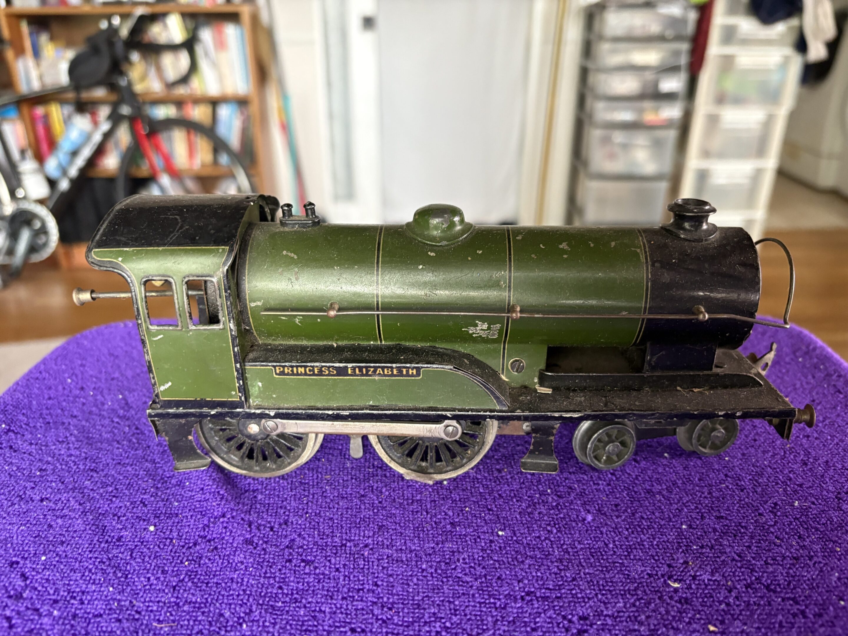 Close-up of a green model steam locomotive on a purple surface.