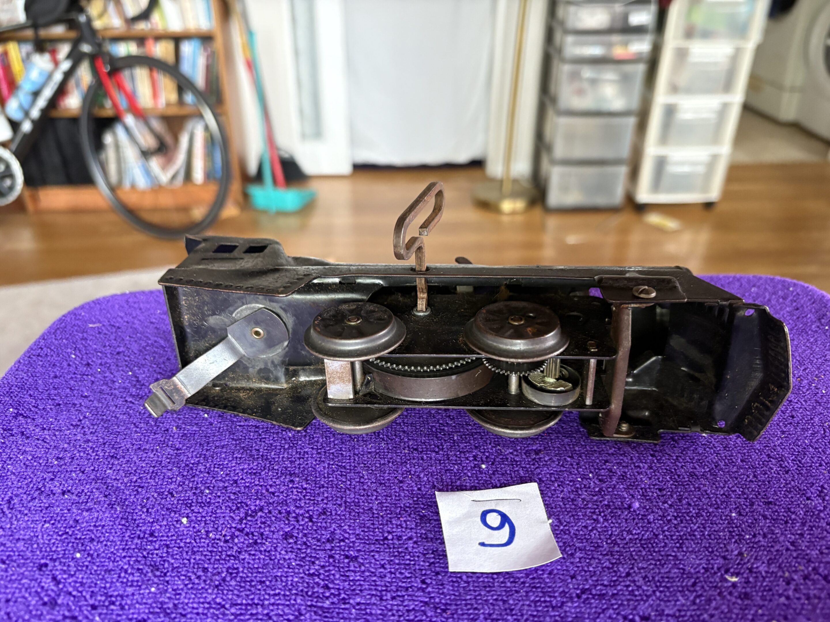 Vintage film camera with a tripod mount on a purple carpet.