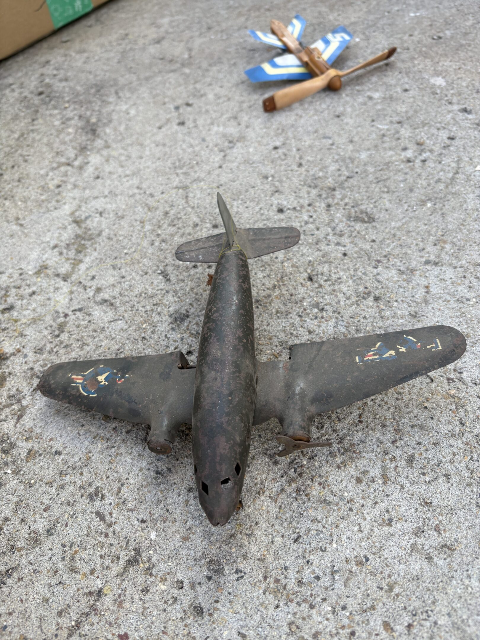 A weathered toy airplane lying on a rough surface.
