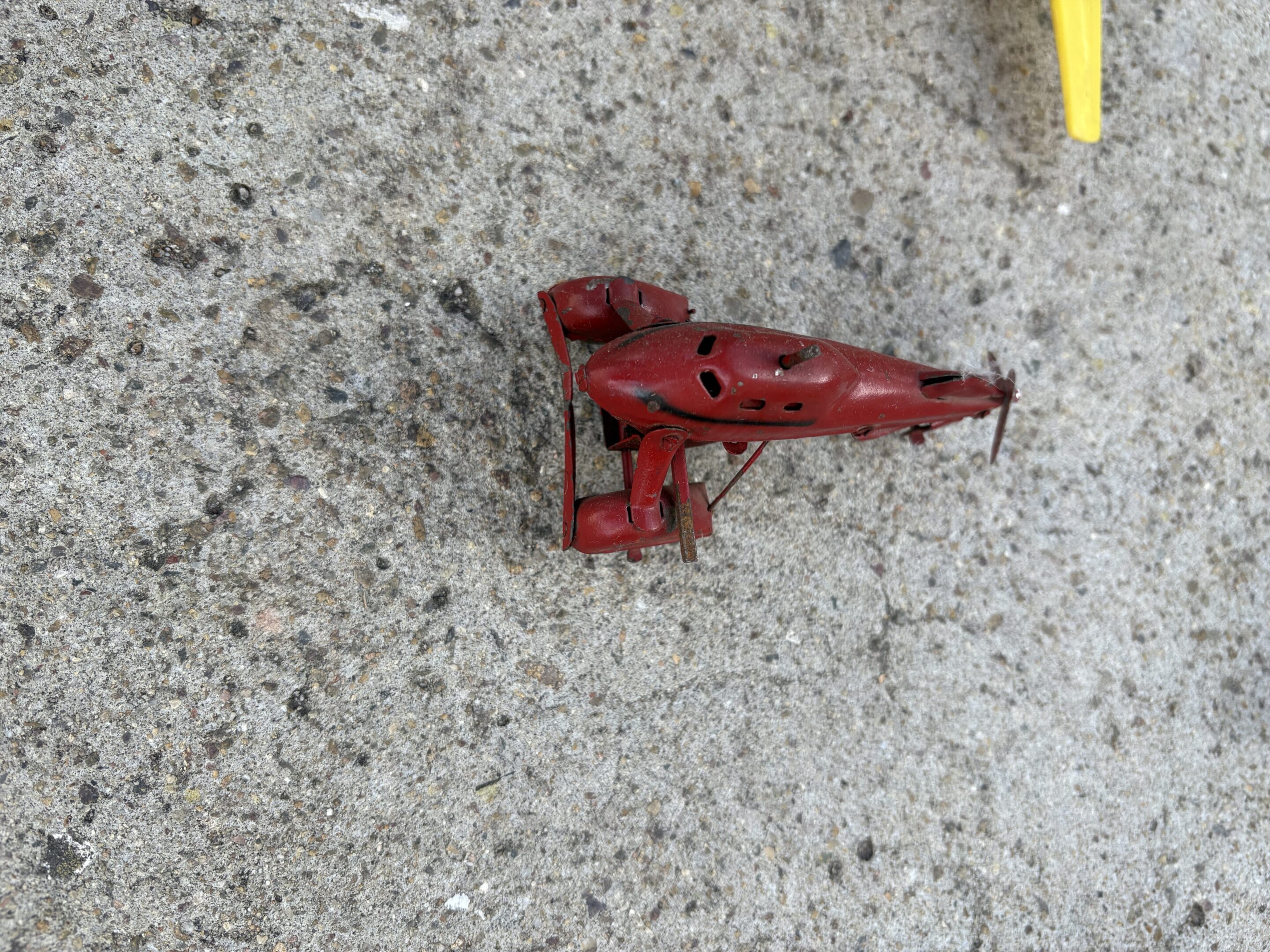 Small red mechanical toy or model on concrete surface.