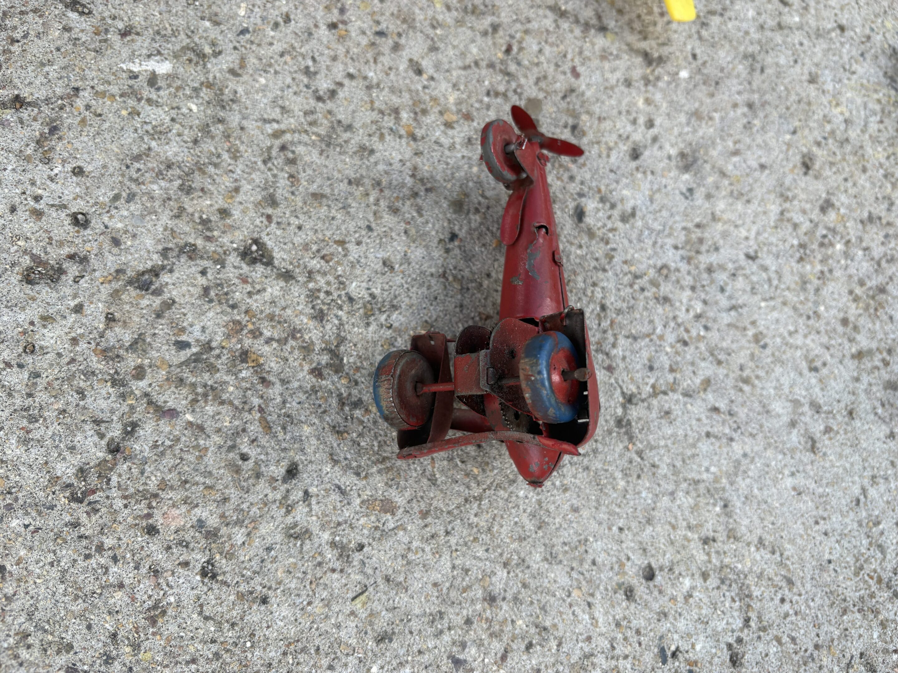 A small red toy tractor on a concrete surface.