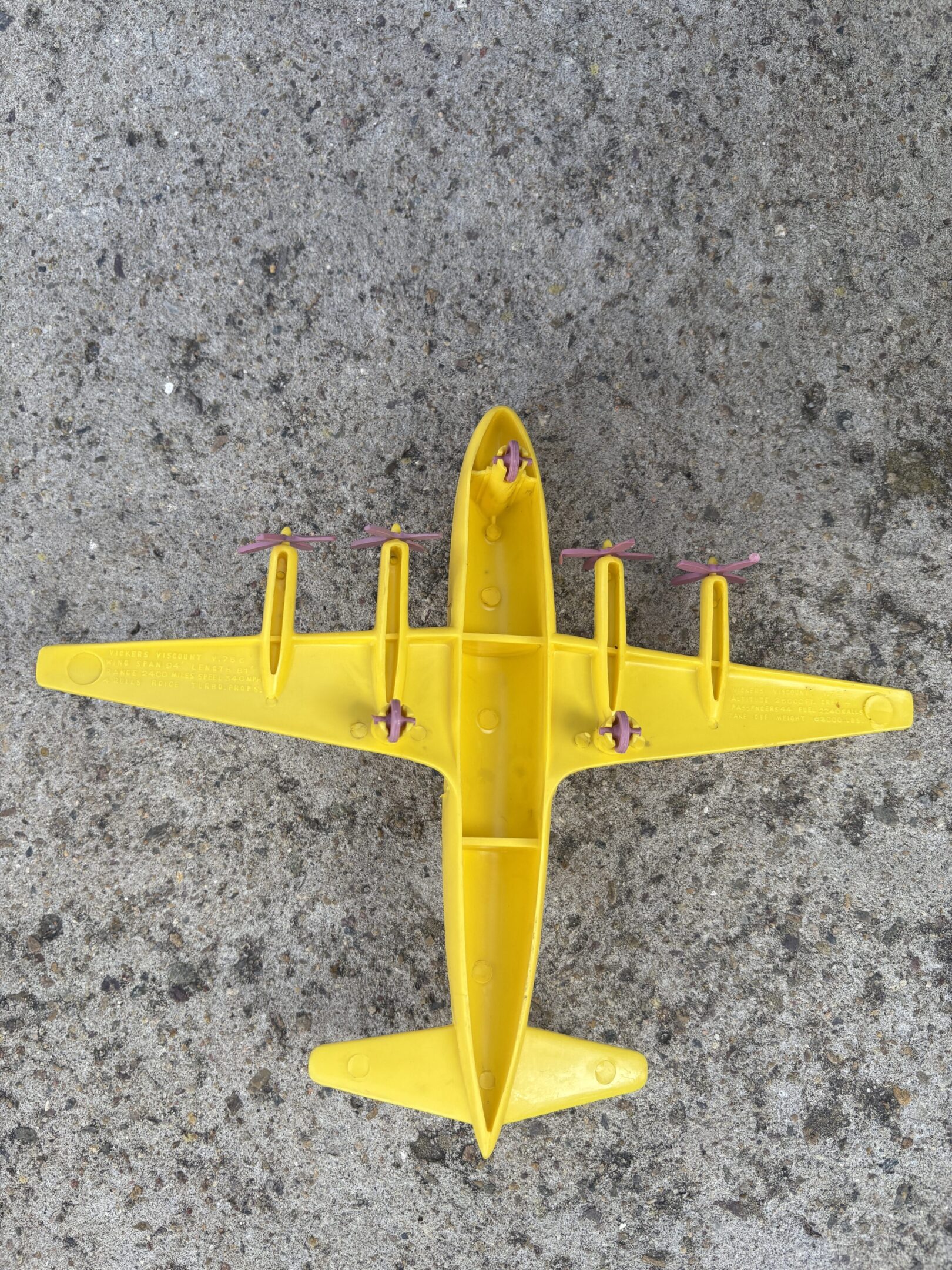 Top view of a yellow toy airplane on a rough surface.