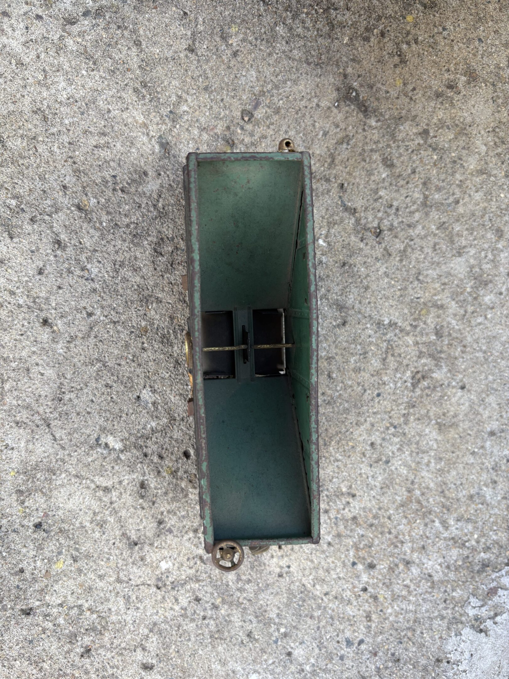 A green rectangular object with black clips on a textured gray surface.