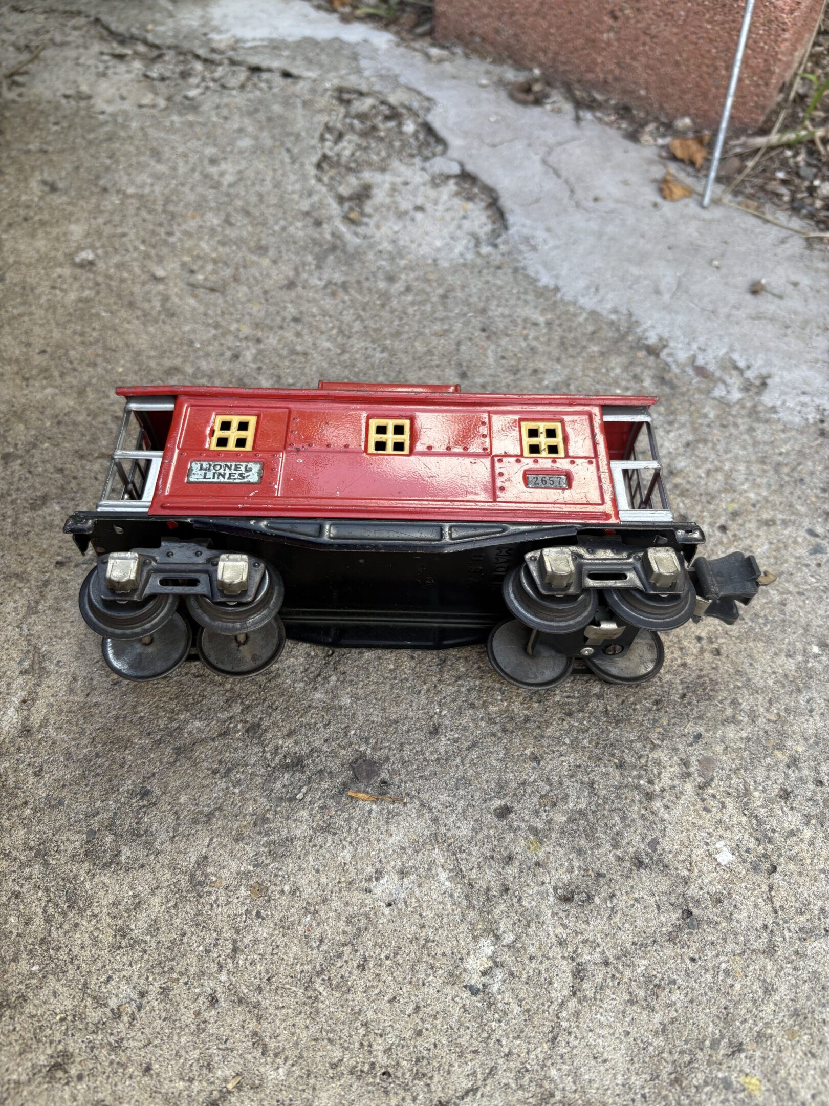 Upside-down vintage toy train car on concrete ground.