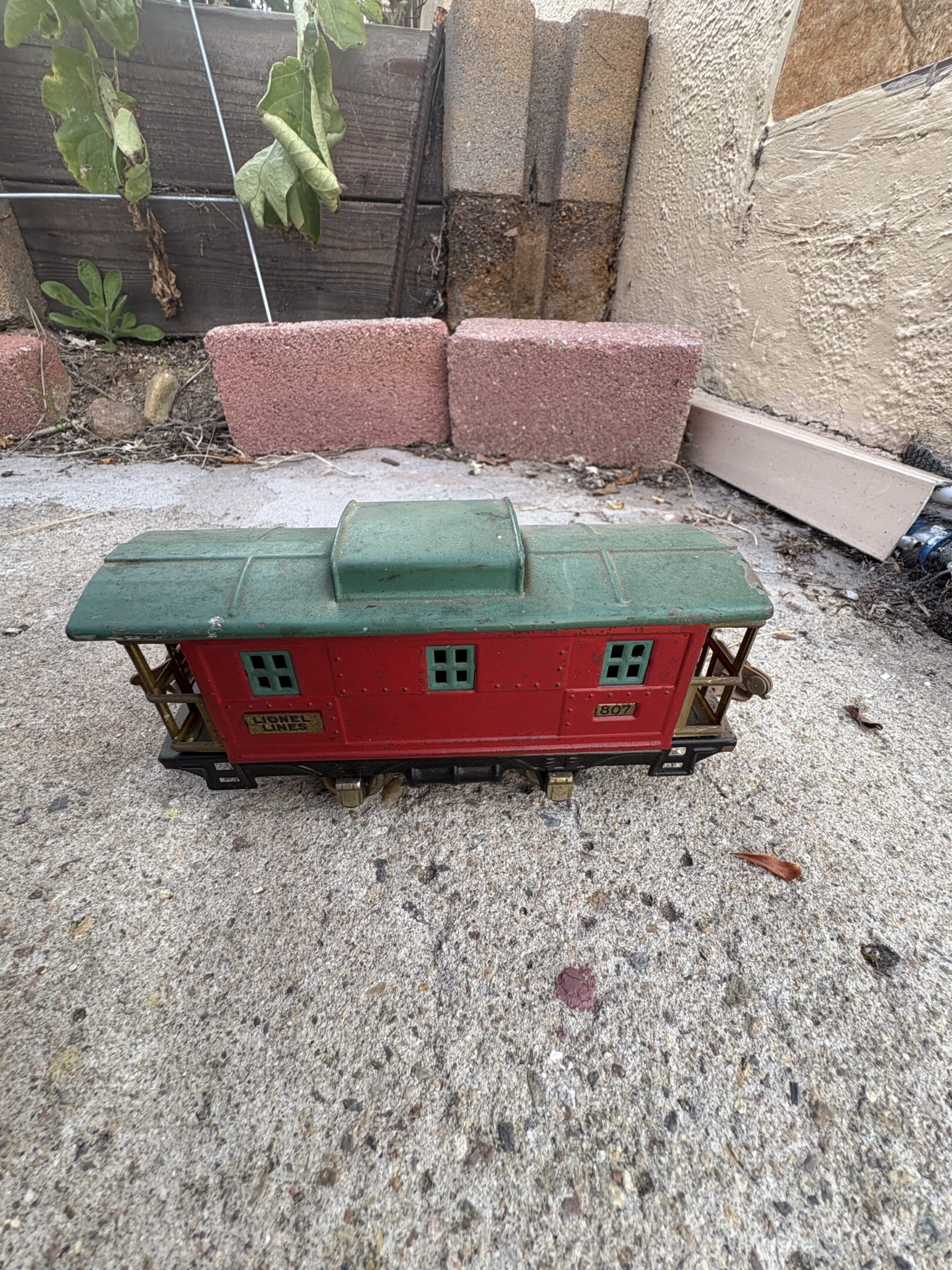 Vintage red and green toy train car on pavement.