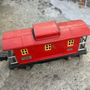 Red toy train car on a concrete surface.