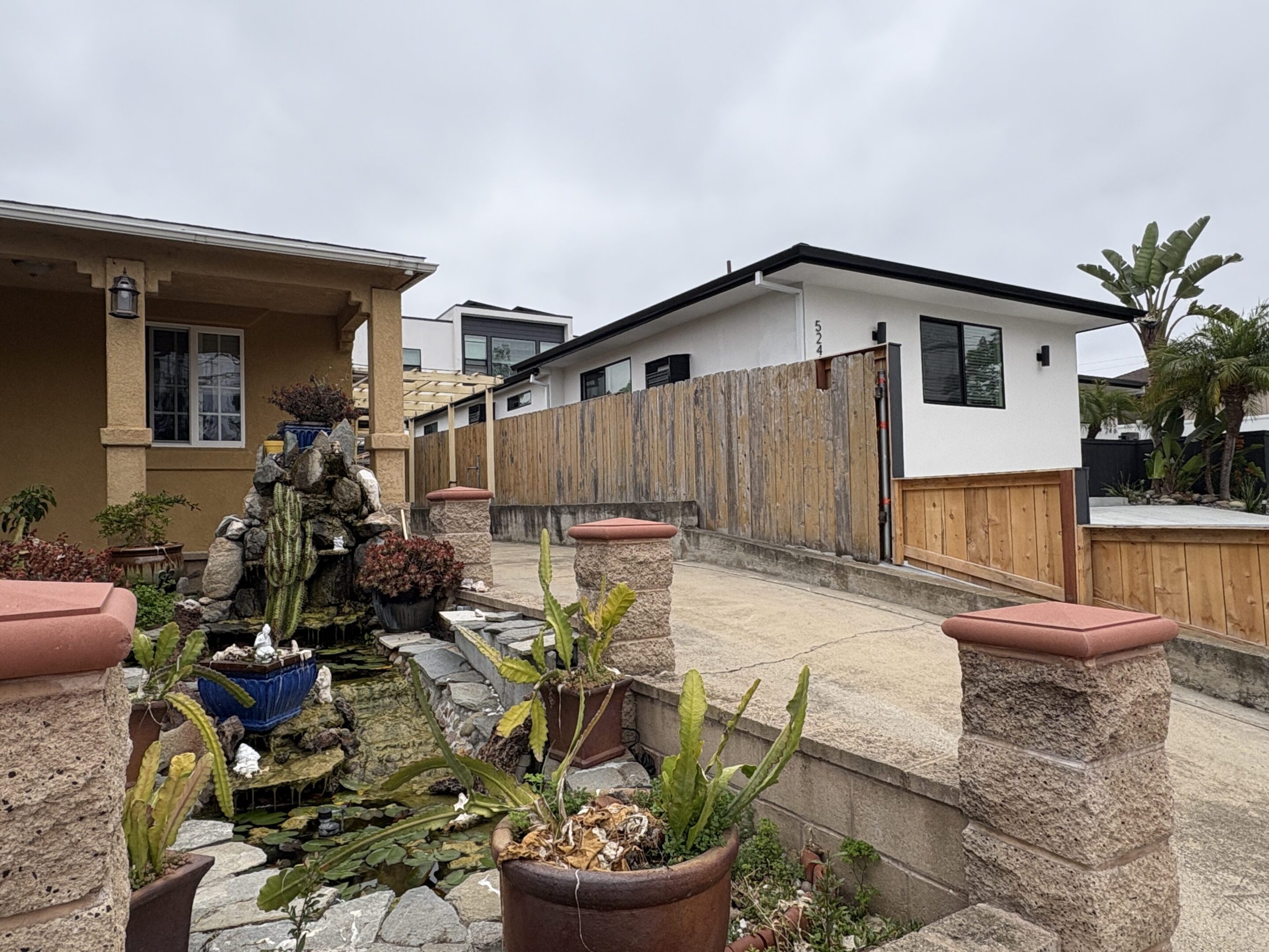 A residential backyard with potted plants and a wooden fence.