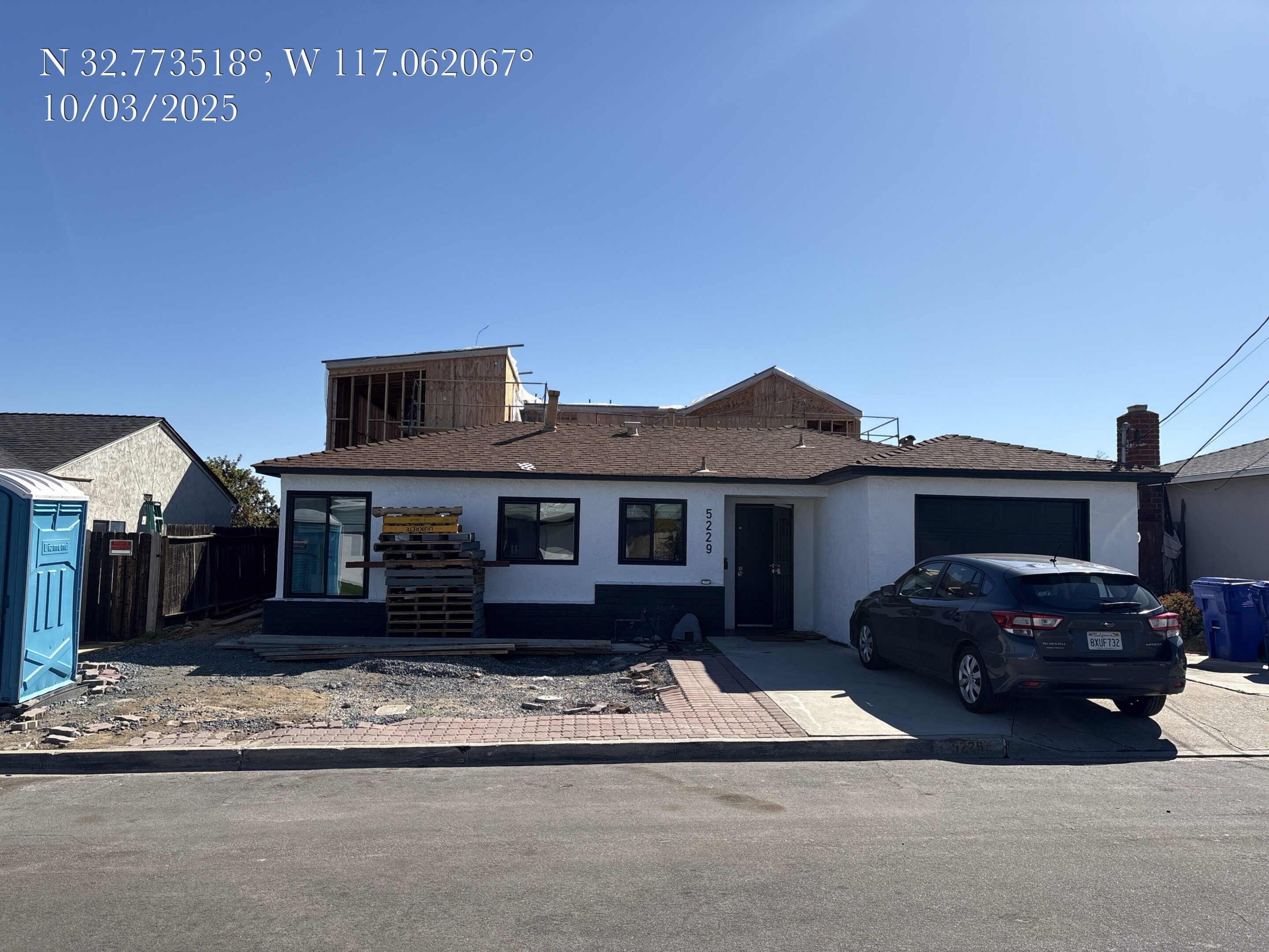 A house with a damaged roof under clear blue sky.