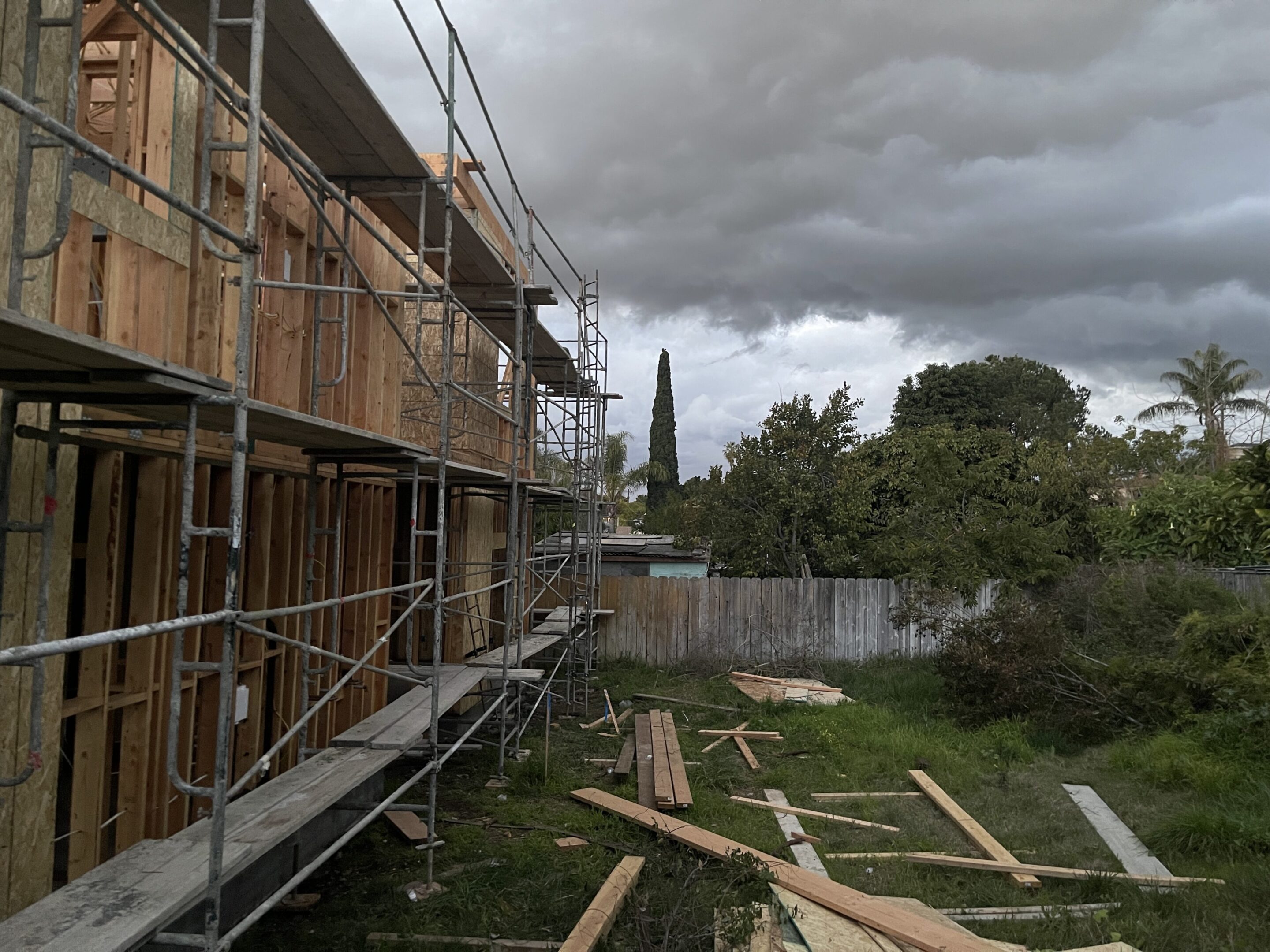 Construction scaffolding and wooden planks under a cloudy sky.