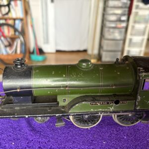 A green model steam locomotive with black and gold details on a purple surface.