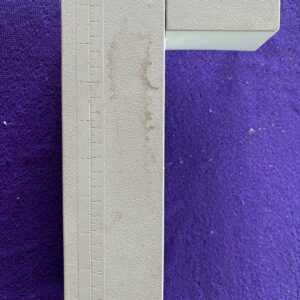 Close-up of a wooden ruler with measurement markings against a purple background.
