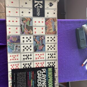 A card game setup with cards and a Keno booklet on a purple surface.