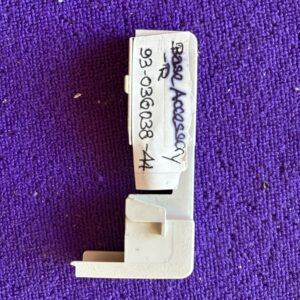 Close-up of a small white plastic component with handwritten text on purple fabric.