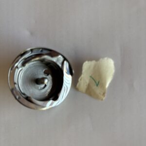 A metal knob and a small piece of torn paper with a handwritten 'N'.