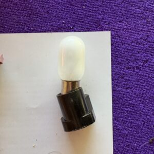 A small light bulb with a black base on a white paper and purple background.