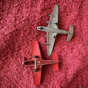 Two model airplanes on a red textured surface.