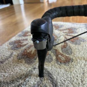 Close-up of a bicycle's handlebar and brake lever on a carpeted floor.