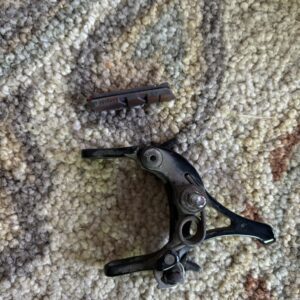 A broken black bicycle brake lever on a carpet.