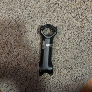 A black bicycle stem lying on a carpeted floor.