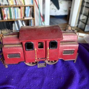 Vintage red toy train engine on a purple cloth.