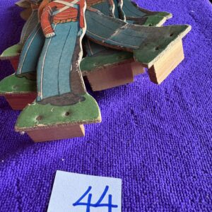 Wooden figurines of two women in traditional attire on a purple cloth.