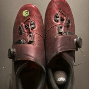 Pair of red golf shoes with a golf ball inside one shoe.