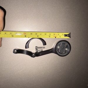 A hand holding a measuring tape next to a small metal compass.