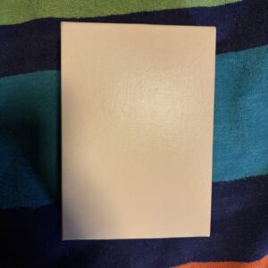 Blank white rectangular sheet on a colorful fabric background.