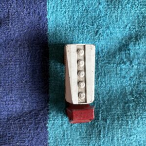 A small white and red object with buttons on a blue fabric.