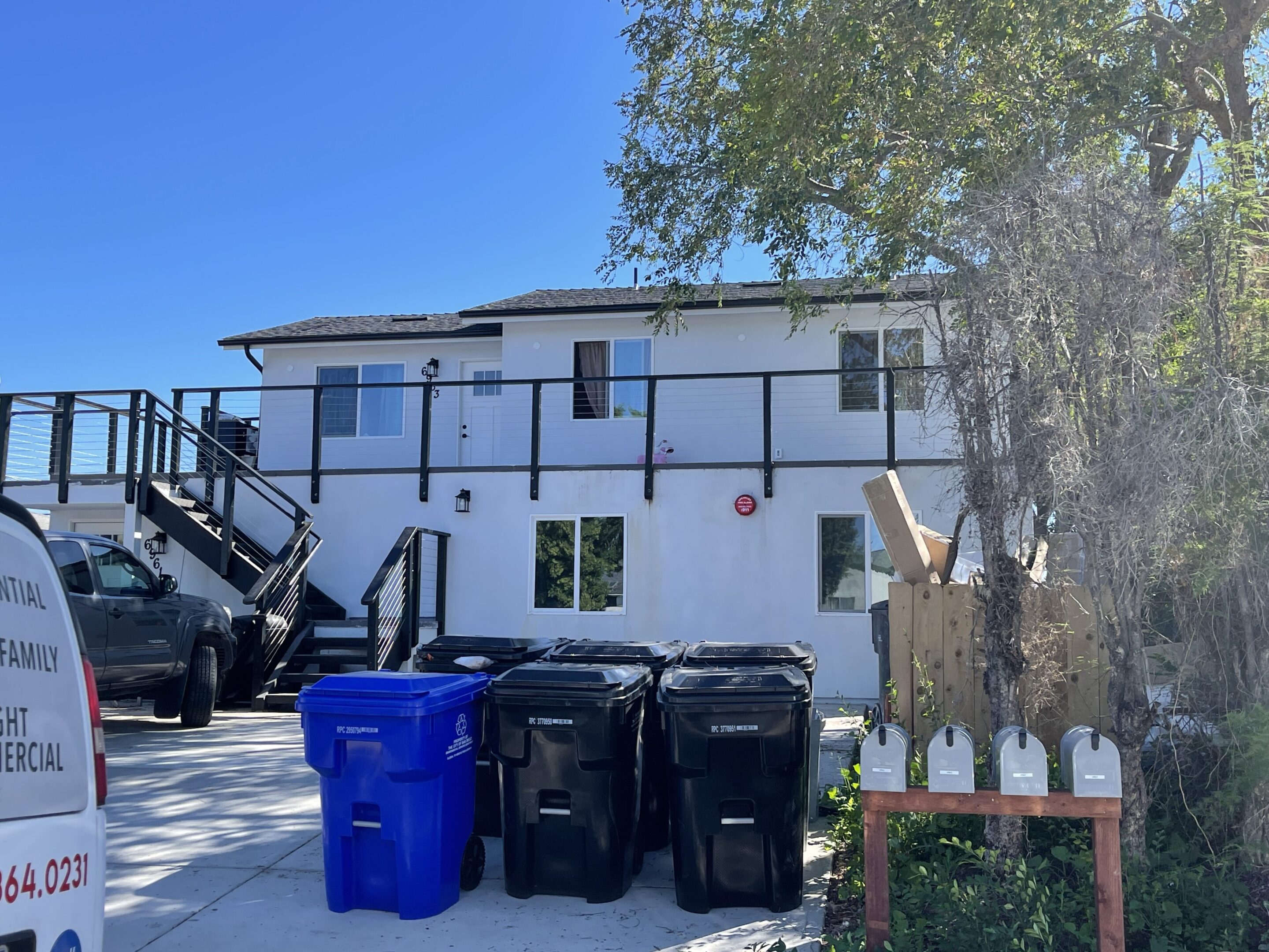 A two-story white building with black trim and multiple outdoor staircases.