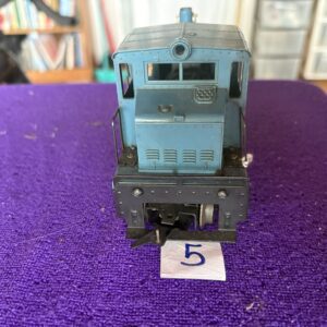 Front view of a blue model train engine on a purple surface.