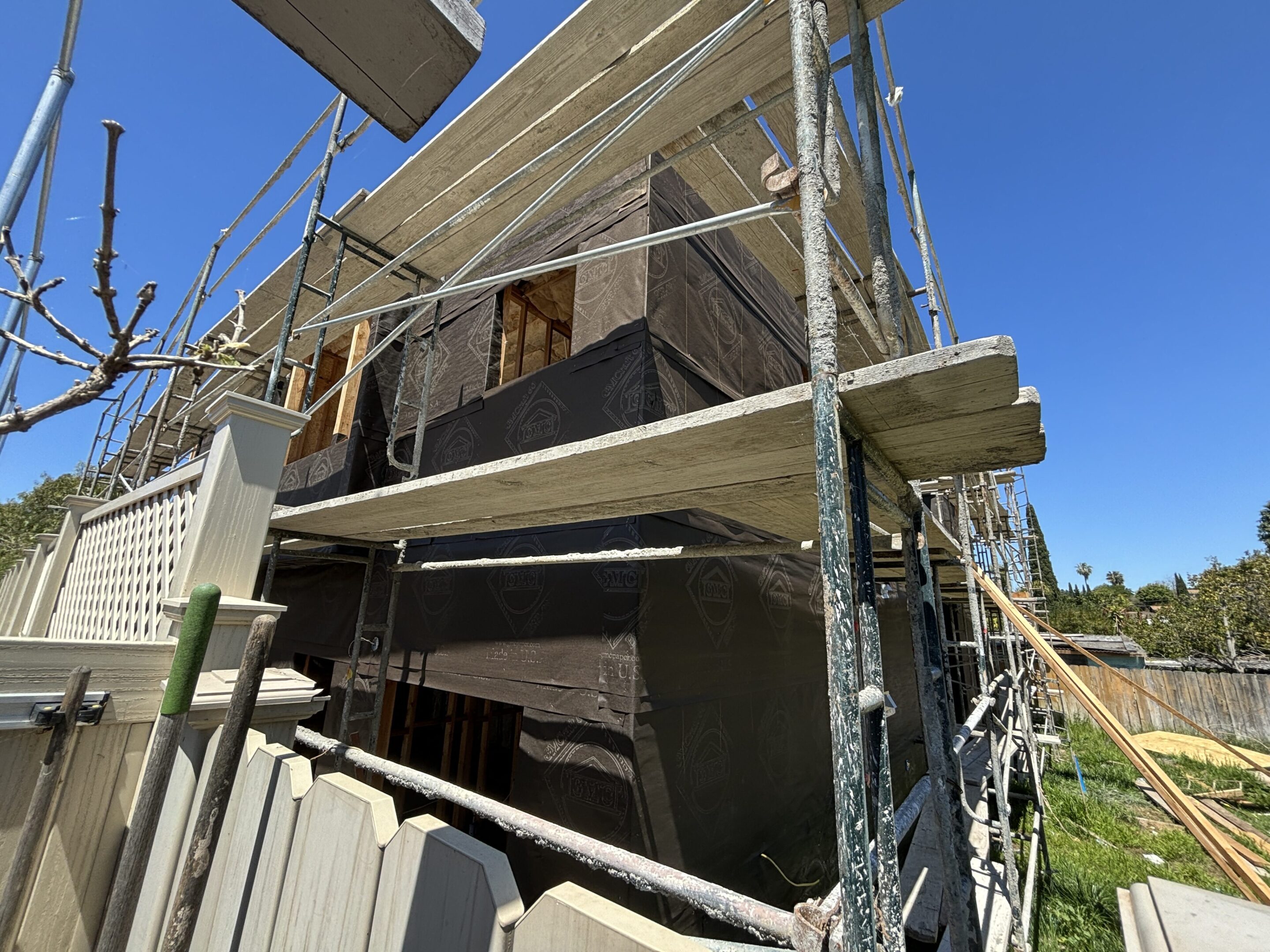 Construction scaffolding around a building under renovation on a clear day.