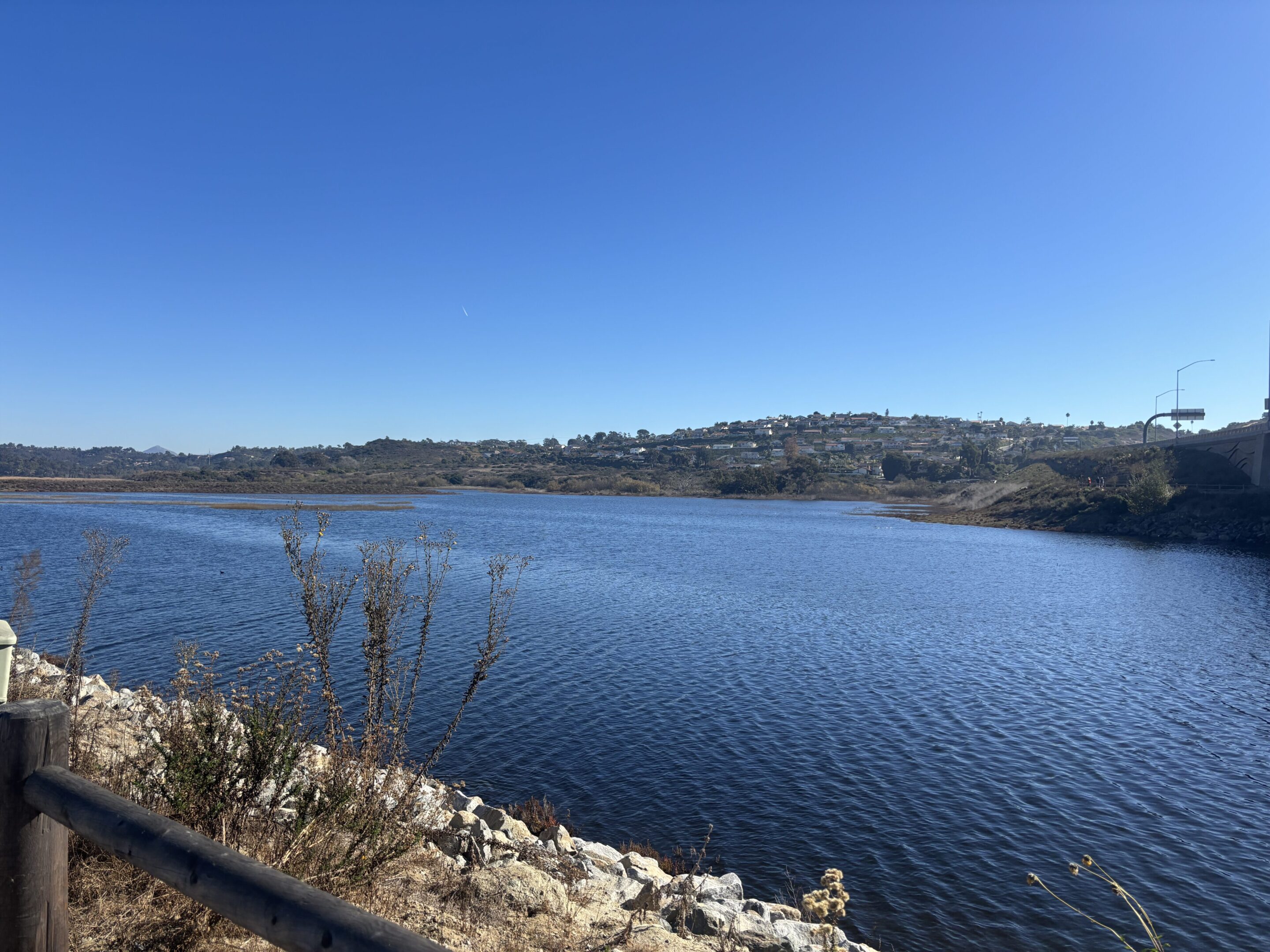 Clear blue lake under a bright sky with rocky shoreline.