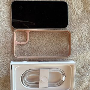 Smartphone with case and charging cable on a soft surface.