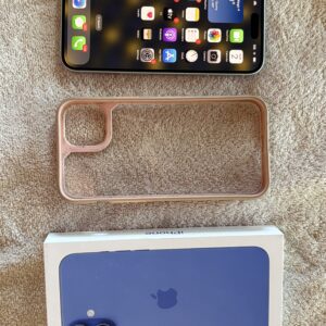 iPhone with a clear case and its box on a beige surface.