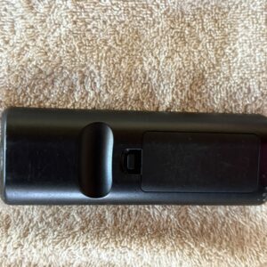 Black TV remote control on a beige carpet.