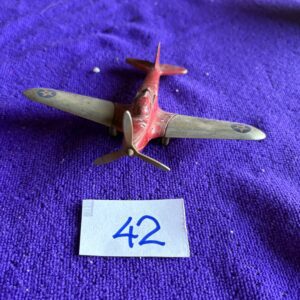 A small vintage toy airplane on a purple cloth with the number 42.