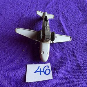 A small metal toy airplane on a purple surface with a note numbered 46.