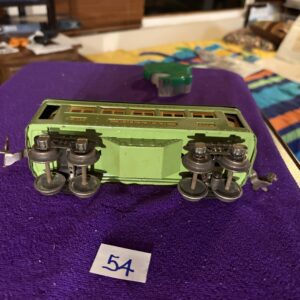 A green toy train car upside down on a purple cloth.