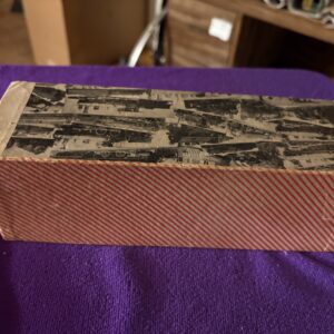 A closed, vintage-style box with a red and patterned design on a purple cloth.