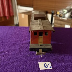 Model train caboose on a purple surface with a number 62 tag.