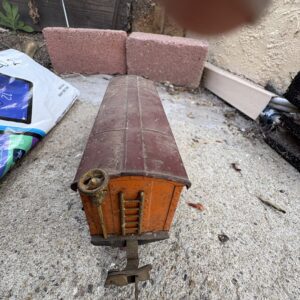 Vintage wooden toy train car resting on a rough surface.