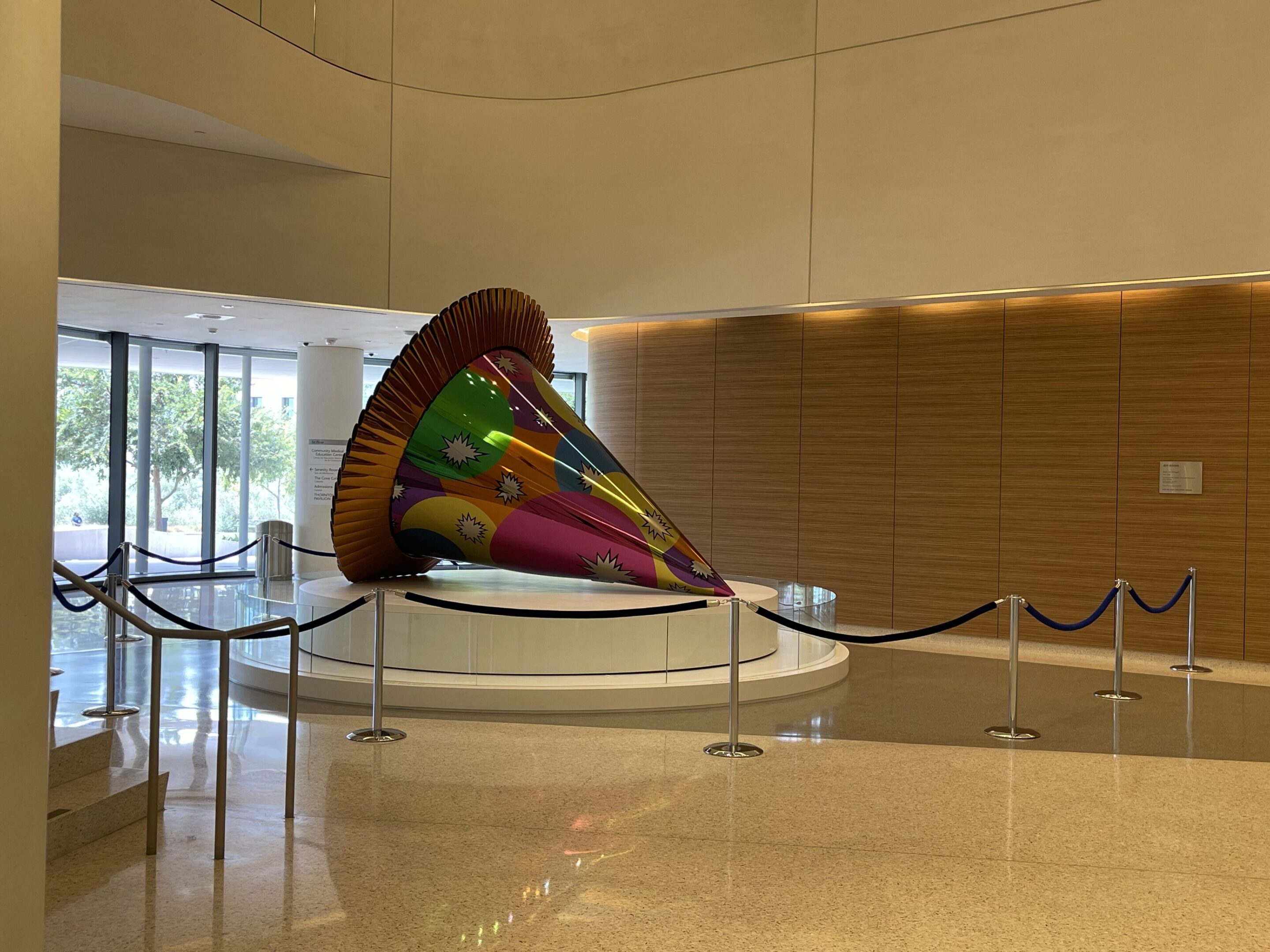 Large colorful spinning top sculpture in a modern indoor space.